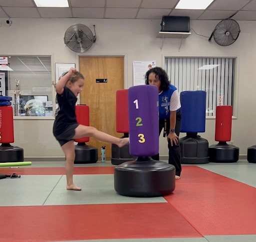 A young student practicing kicks with an instructor at Azad's Martial Arts Center in Chico, CA